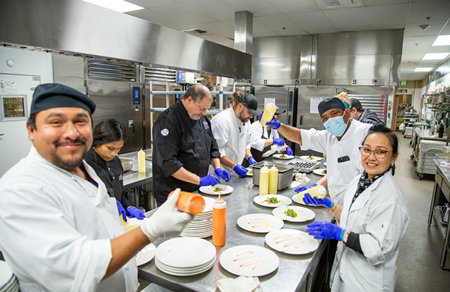 A scene in the kitchen of the 2023 Raising Hands event, showing the chef and the kitchen staff busying preparing the evening's meal. 