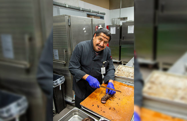 The chef preparing a dish for the 2023 Raising Hands event, smiling at the camera. 