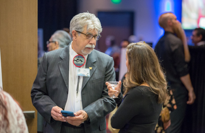 Tulalip Tribes’ 2018 Raising Hands photo of volunteer with a file folder speaking with a guest.