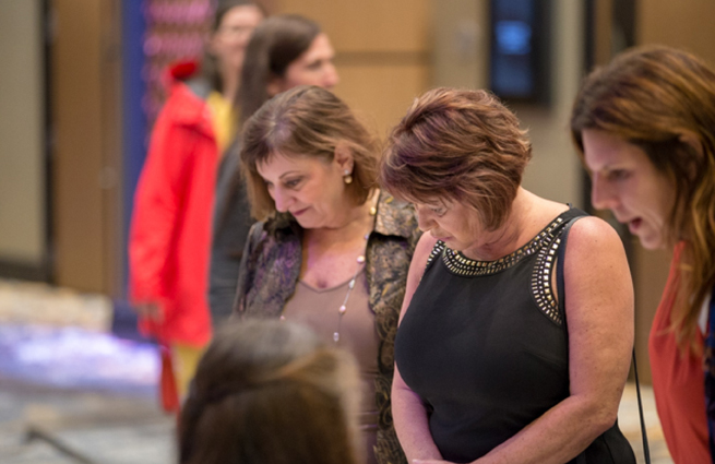 Tulalip Tribes’ 2018 Raising Hands photo of volunteer handing two guests a complimentary gift bag.