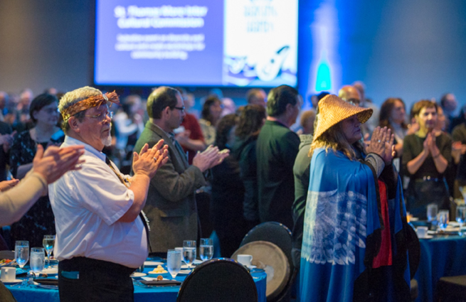 Tulalip Tribes’ 2018 Raising Hands photo of a ceremony with traditional singing from the group’s right.